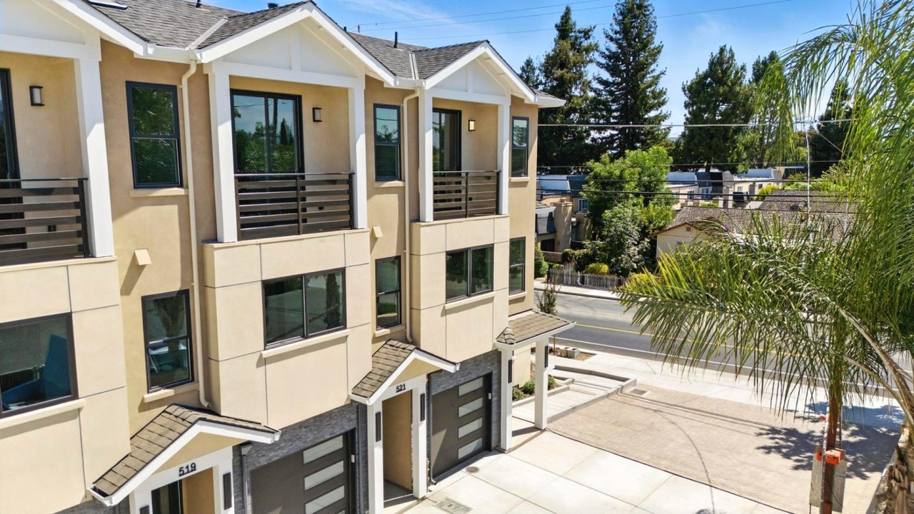 Residential exterior with cream walls, white trim, balconies and dark garage doors